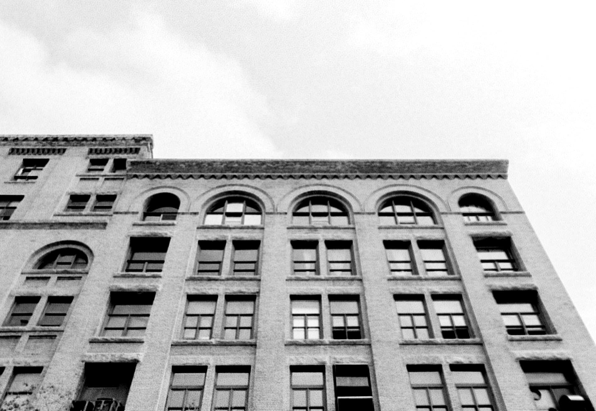 Looking up at the arched windows and cornice of a historic Winnipeg building