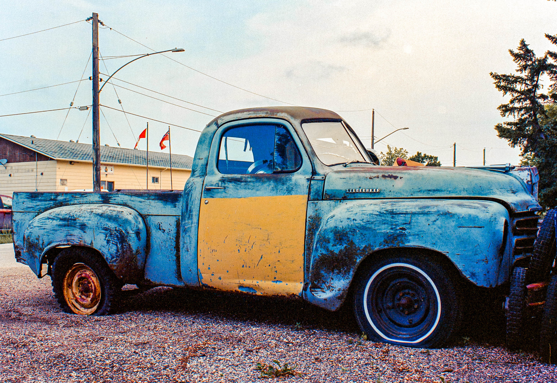 Studebaker — a weathered blue and yellow pickup truck parked on gravel